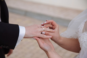 Obraz na płótnie Canvas marriage hands with rings. groom wears the ring on the finger of the bride at the green background