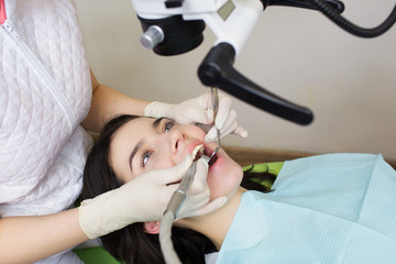 professional dentist examination patient with microscope at the office.Dentist looking through microscope at surgery office