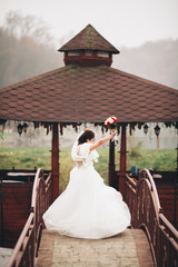 Fototapeta premium Beautiful luxury bride posing with a bouquet outdoors 