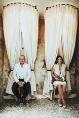 Stylish happy bride and groom sitting