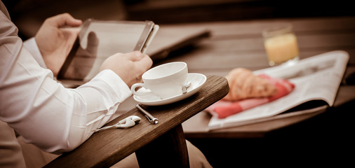 Young Man Eating Breakfast Whilst Using Tablet