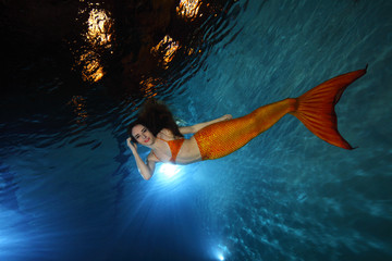 Mermaid swimming underwater in the pool 