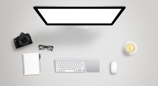 Isolated computer display for mockup on work desk with keyboard, mouse, coffee, camera, notebook, glasses, pencil.