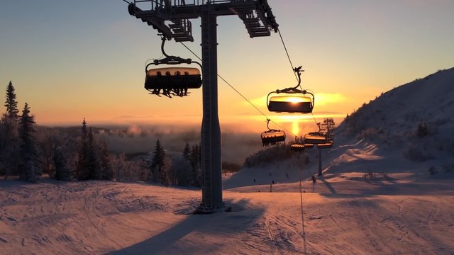 cableway in the rays of the setting sun among snow-capped mountains