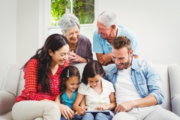 Smiling multi generation family using digital tablet 