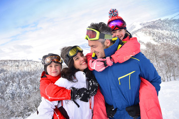 Parents giving piggyback ride to kids on ski slope