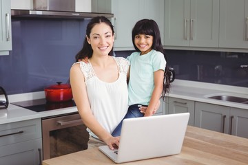 Portrait of smiling mother and daughter using laptop