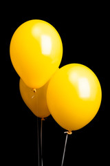 Three yellow balloons isolated on black