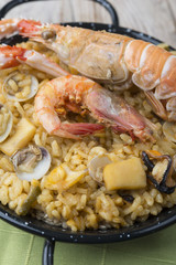 Vegetable paella with seafood on a wooden background
