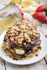 Pancakes with banana , walnut & chocolate on wood background