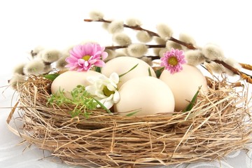 Fototapeta na wymiar Easter white eggs in the nest with pink and white flowers