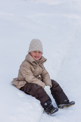 Fototapeta na wymiar cheerful girl fell into a large snow drift and laughs 