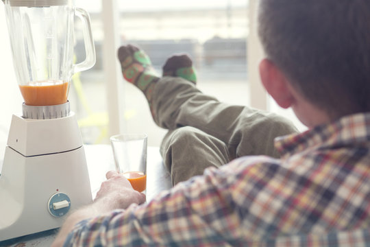 Man Sitting At Table Next To A Juicer