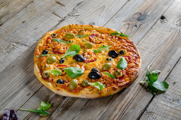 Delicious pizza with cheese and black olives on wooden table, view from above.