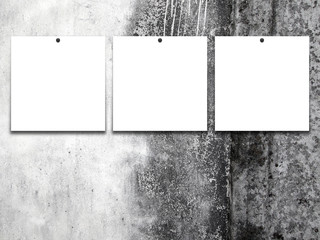 Close-up of three square blank frames with pins on dirty rough wall background