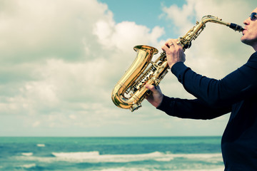 Saxophonist playing on saxophone on blue sky background