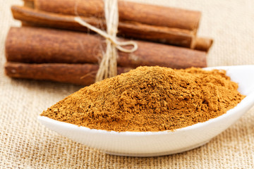 Cinnamon sticks with cinnamon powder on wooden background, Selective focus
