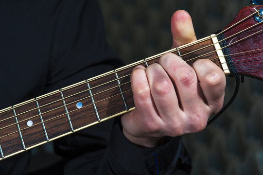 Man's hands playing on acoustic guitar, closeup.