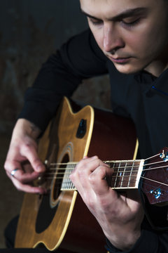Young man playing on acoustic guitar. Selective focus.
