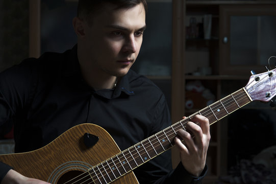 Portrait of young man playing on guitar