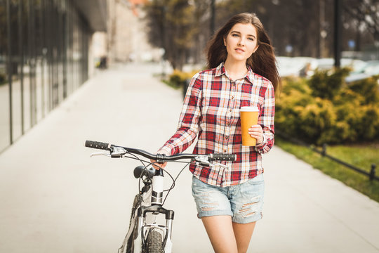 Young beautiful woman with coffee cup and a bicycle