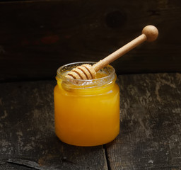 natural honey in a jar with honey spoon on a wooden rustic vintage table
