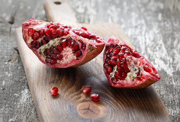 Pomegranate with arils on brown wooden board
