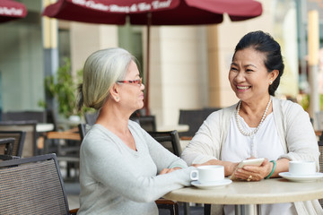 Two cheerful Vietnamese women chatting in cafe