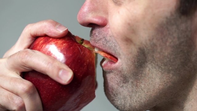 Closeup of a unshaven man eating an apple