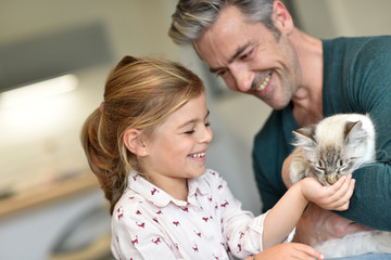 Daddy with little girl petting cat at home