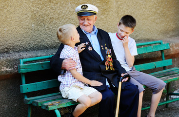 Obraz na płótnie Canvas WWII veteran with children. Grandchildren looking at grandfather