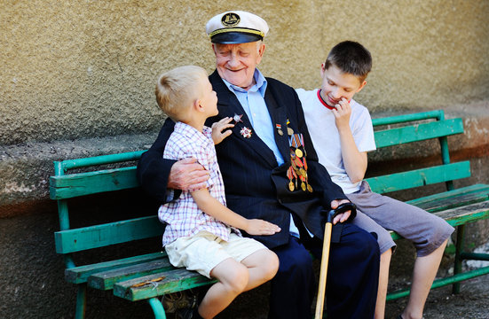 WWII Veteran With Children. Grandchildren Looking At Grandfather