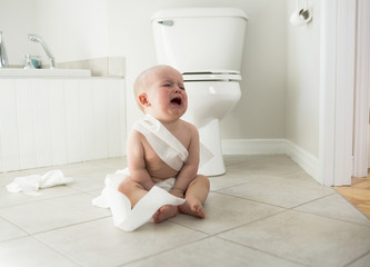 Adorable baby boy playing with toilet paper