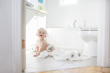 Adorable baby boy playing with toilet paper
