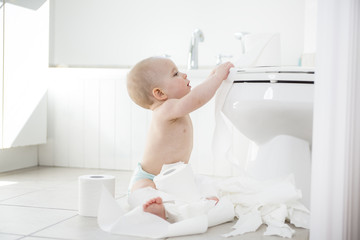 Adorable baby boy playing with toilet paper