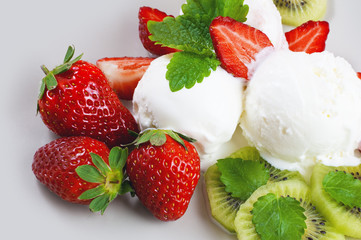 Butter and strawberry ice cream balls on the plate. Strawberries, kiwi, lemon balm