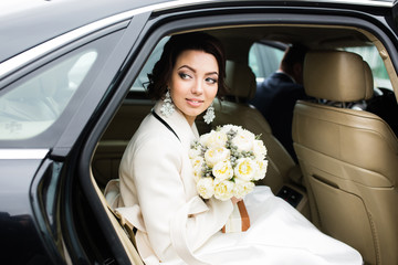 Wedding Day: beautiful bride with bouquet of white flowers in the car