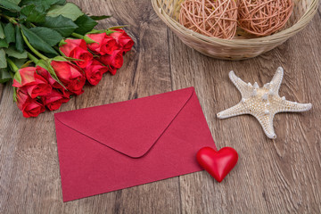 Red envelope, red roses and starfish on a wooden background