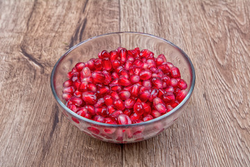 Fresh organic pomegranate seeds in a bowl on a background