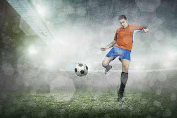 Obraz na płótnie Canvas Soccer player with ball in action at stadium under rain.