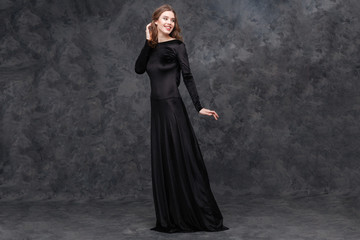 Fototapeta na wymiar Portrait of charming young woman in long black dress