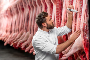 Butcher measuring pork temperature in the refrigerator at the meat manufacturing