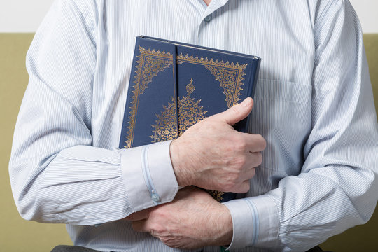 An old man hands holding the Koran
