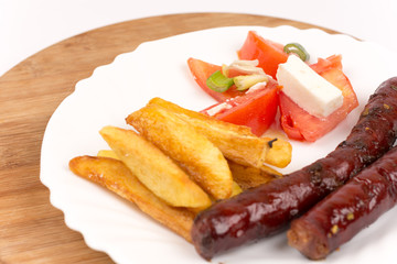 Grilled homemade red sausages with potatoes and tomatoes