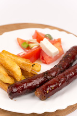 Grilled homemade red sausages with potatoes and tomatoes