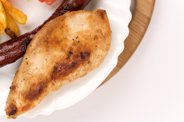 Chicken breasts and grilled red sausages on the plate