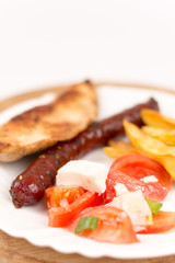 Chicken breasts and grilled red sausages on the plate
