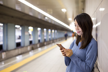 Woman use of mobile phone in train station