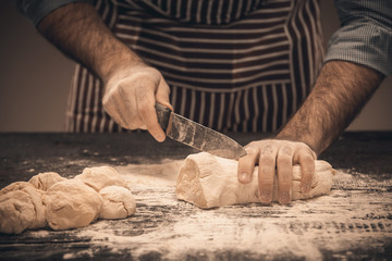 Male hands cut the dough.