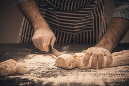 Male hands cut the dough.